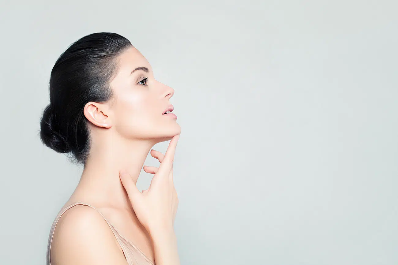 Photo de profile stylisee d une jeune femme mettant son doigt sous le menton lipofilling lipomodelage du visage un procede naturel pour redonner du volume | Dr Christophe Reinbold Lyon