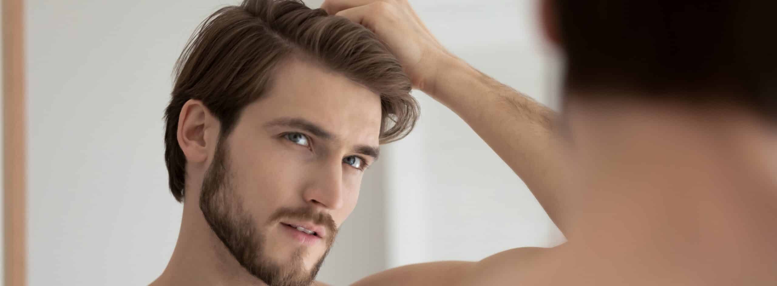 Photo de profile d un jeun homme se touchant les cheveux chute des cheveux comment prevenir et soigner la calvitie | Dr Christophe Reinbold Lyon