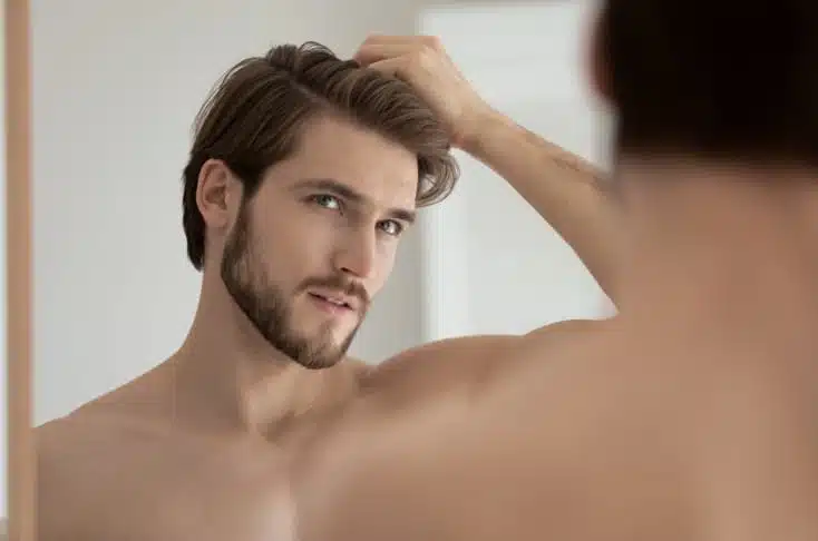 Photo de profile d un jeun homme se touchant les cheveux chute des cheveux comment prevenir et soigner la calvitie | Dr Christophe Reinbold Lyon