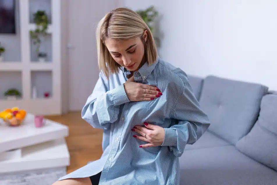 Jeune femme portant une chemise d homme regardant son sein Quelle prothese mammaire choisir | Dr Christophe Reinbold Lyon