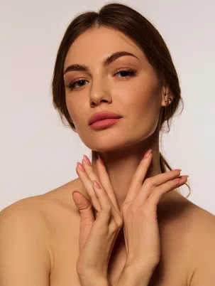 Portrait d'une femme avec les mains posées près du visage - médecine esthétique - Dr Reinbold | Lyon